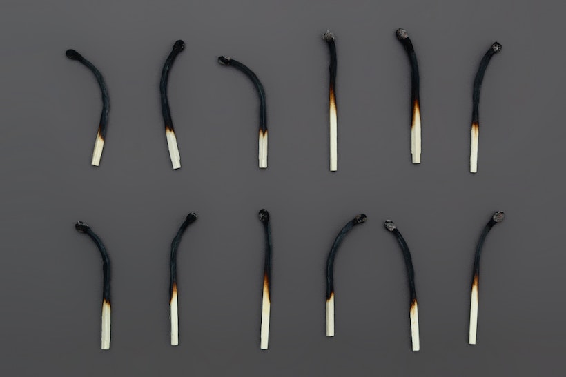 12 burned out matchsticks on a gray background